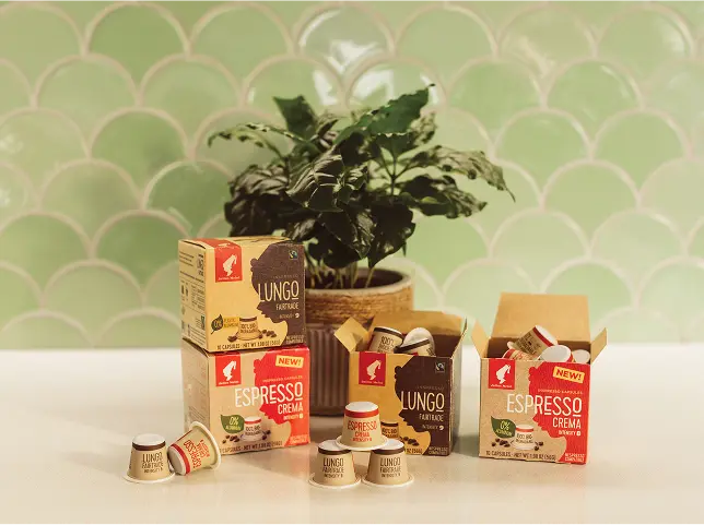 Julius Meinl Inspresso kafijas kapsulu sortiments uz koka virsmas ar fonu
