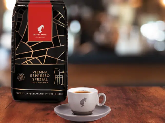 Vienna Espresso Spezial kafijas iepakojums ar Julius Meinl baltu kafijas tasīti uz šķīvīša